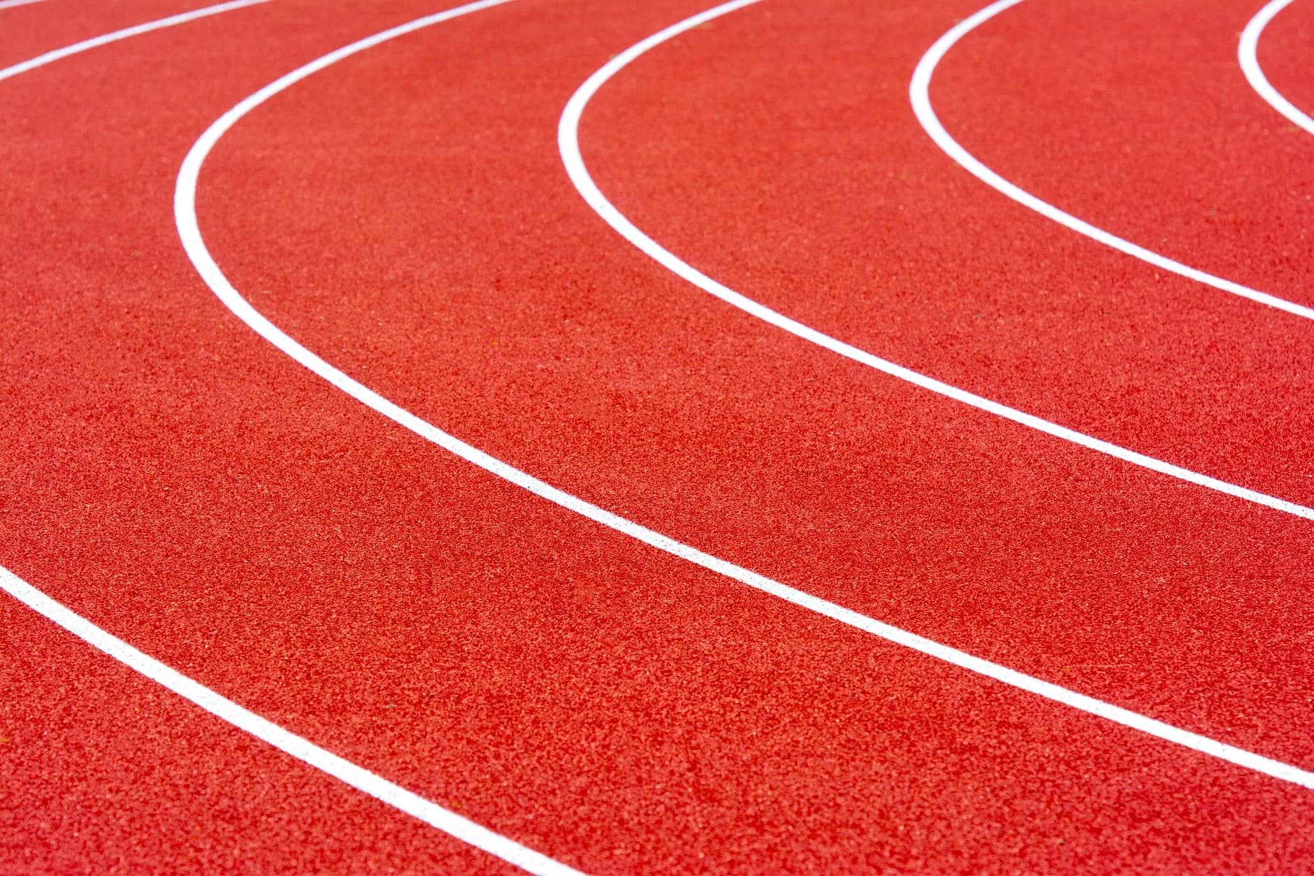 Red running track with curved white lane markings at a sports stadium